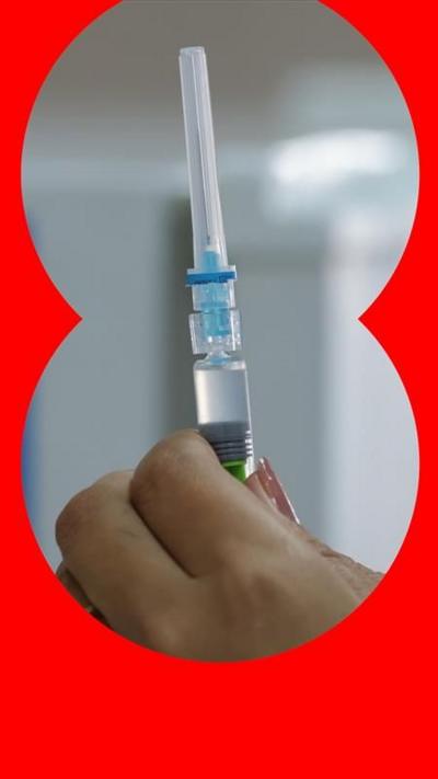 A health worker, with painted nails, prepares a dose of a vaccine