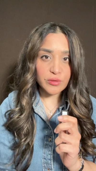 Woman with long dark hait and denim jacket holding small mic