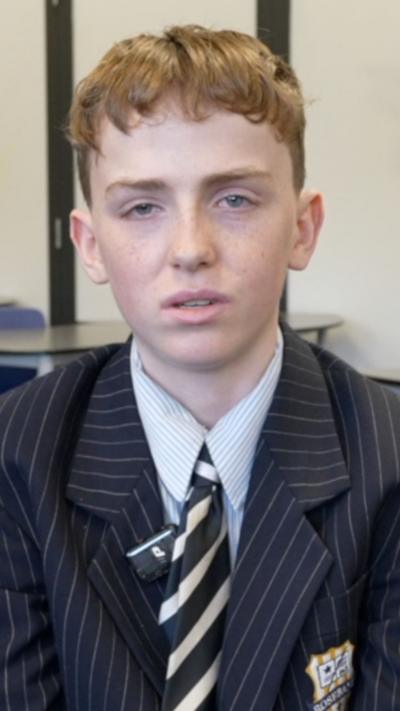 Boy sitting in classroom wearing a school uniform