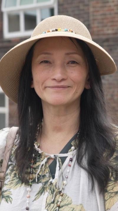 A Japanese woman with long hair, a straw hat and white patterned top