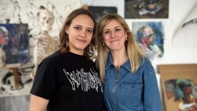 polina and jenny standing together smiling at the camera in an art room