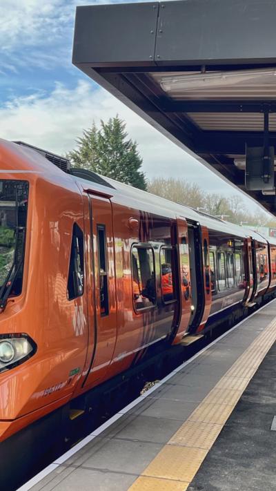 An orange passenger train stopped at a station
