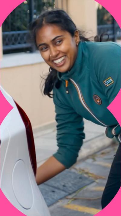 A woman wearing a green zip up jumper smiles at someone off camera