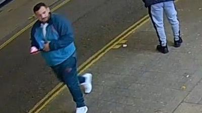 Man caught on CCTV wearing a tracksuit holding a phone