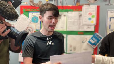 a young man looking excited while holding a white piece of paper