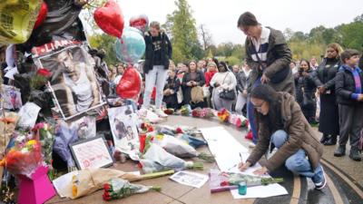 A fan writes a message during a vigil for 31-year-old One Direction singer Liam Payne from Wolverhampton