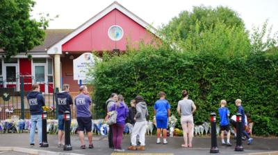 People gather to lay flowers outside school 