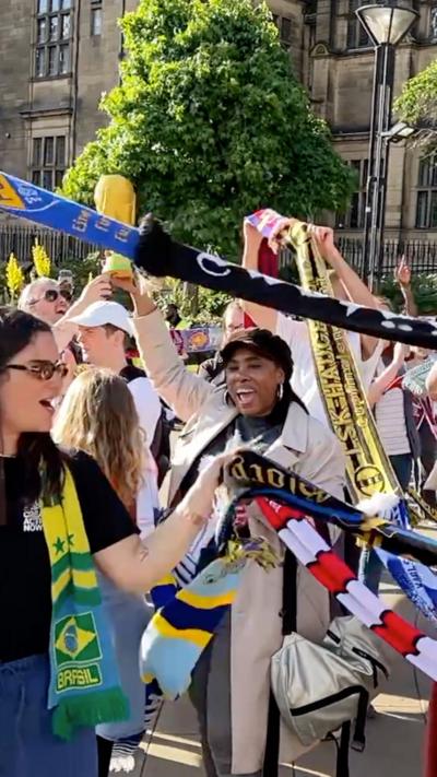 A group of people holding up football scarves and smiling