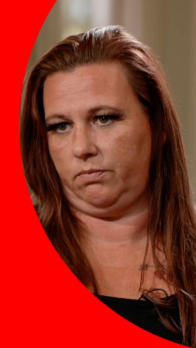A woman with long red hair looks at someone off-camera