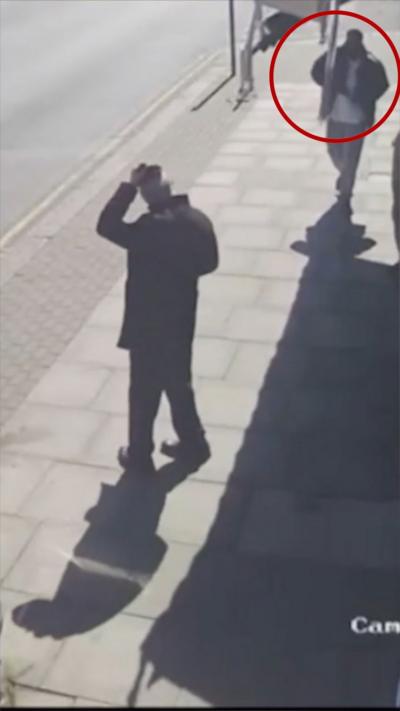 Red circle around a man walking towards another man standing by bus stop