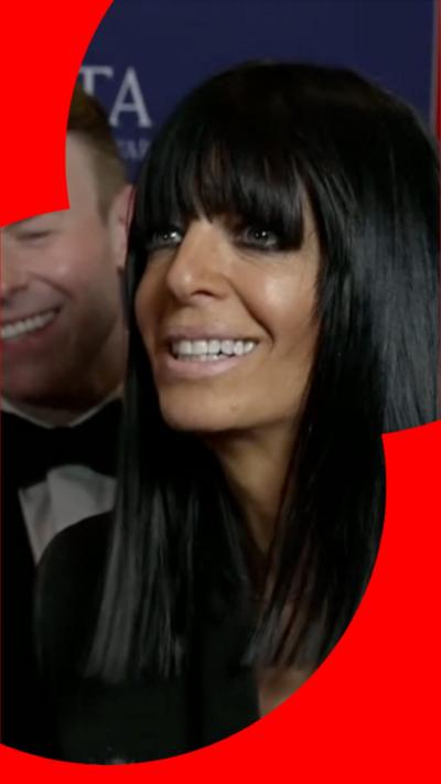 A woman with shoulder-length dark hair and a heavy fringe smiles at someone off-camera
