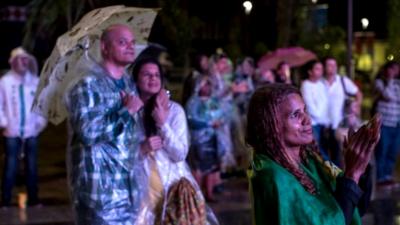 People watch the Rio 2016 Olympics closing ceremony in the rain at the Olympic Boulevard live site