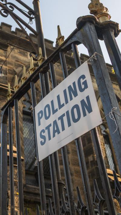 A polling station sign on an iron gate.