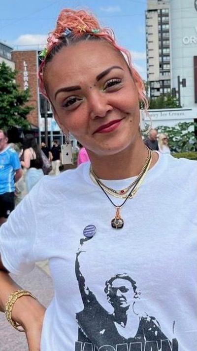 A woman with scraped back hair wearing a white t-shirt 