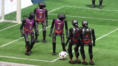 Five humanoid robots, on playing football on field