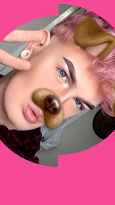 Person takes a selfie using AR lenses. The photo has applied a dog nose to their face.