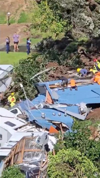 Emergency workers search through wreckage of New Zealand campsite after it was hit by a landslide.