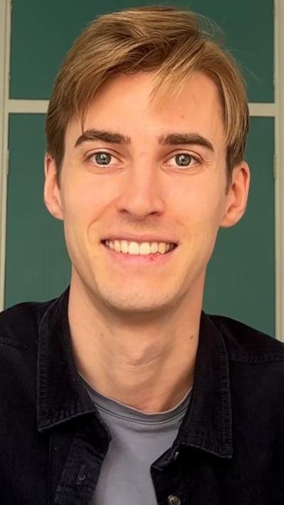 A man with short brown hair smiles at the camera