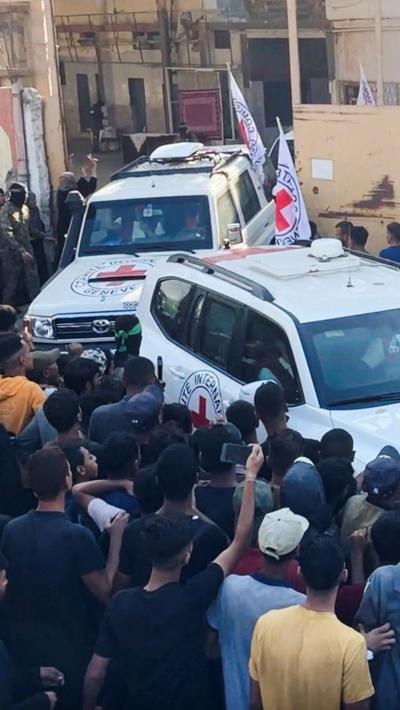 Red cross vehicles pass through crowds as they leave carrying hostages in Gaza City on Monday.