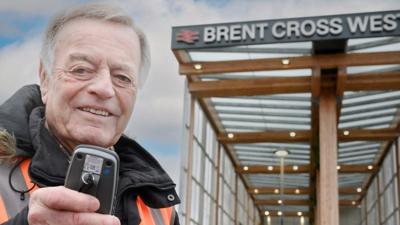 Tony Blackburn holding infront of Brent Cross West sign