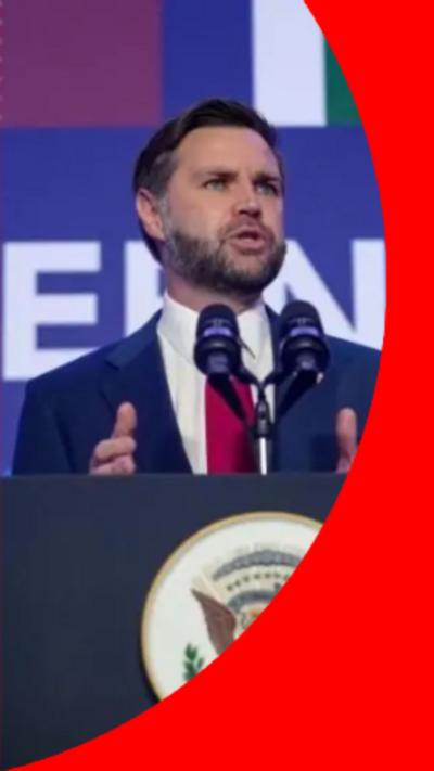A man with short dark hair and a short beard stands behind a podium
