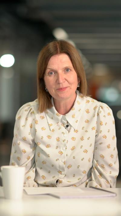Bethan Lewis, who has short brown hair, wearing a white collared shirt with yellow markings 