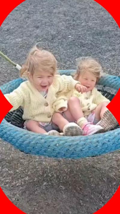 Two four year old girls laughing on a swing