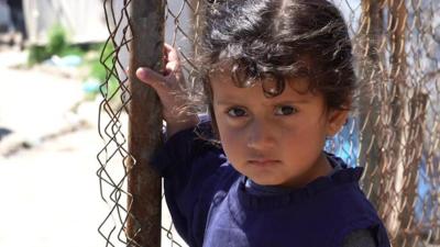 A-young-girl-holds-a-fence.