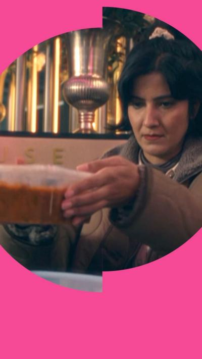 A woman holds a plastic container with food in it