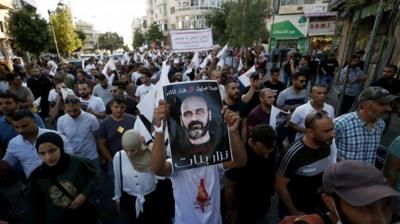 A man holds up a poster of Nizar Banat at a protest in Ramallah, in the occupied West Bank (2 August 2021)