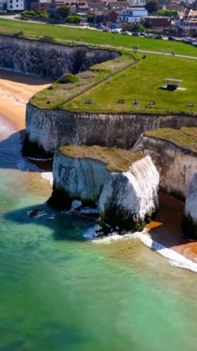 Arial shot of grass topped white cliffs above the sea