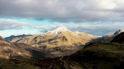 a-mountain-range-in-the-sunlight-with-snow-on-the-peak