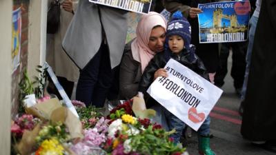 Mum and child laying flowers at scene of terror attack