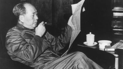 Chairman Mao smoking and reading a newspaper