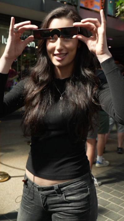Vanessa holding up a pair of solar eclipse glasses to her face and smiling.
