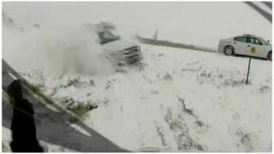 A man seems oblivious as truck careens off a motorway and plummets towards him down a snowy verge.