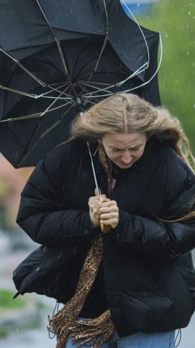 Woman holding umbrella that has blown inside out.