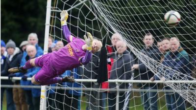 Welders' goalkeeper Michael Dougherty fails to save a Glenavon free-kick from Andy Hall