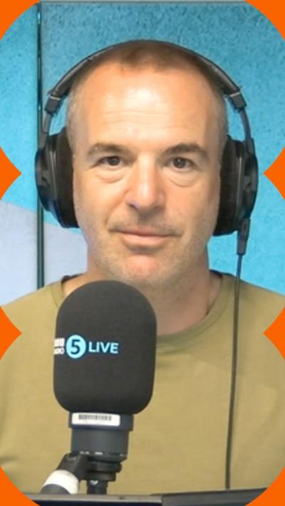 A man with short hair stands in front of a microphone