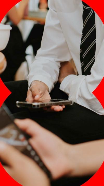 Schoolchildren in uniform looking at their phones.