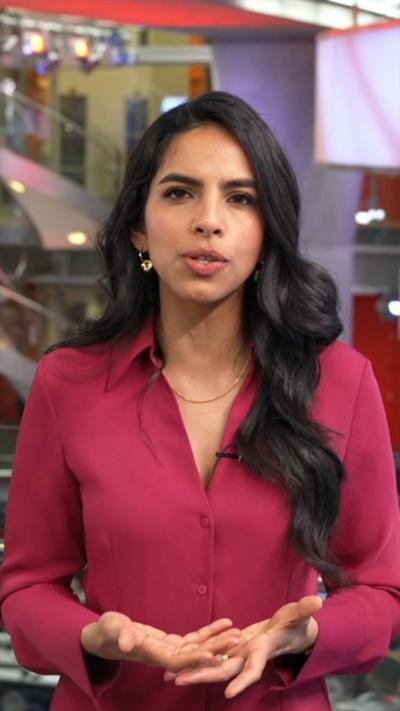 A woman with long black hair wearing a pink shirt.