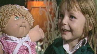 A child next to a Cabbage Patch Doll