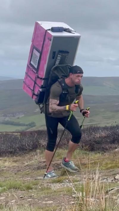 Matt Jones hiking with fridge freezer on his back