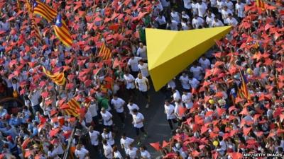 Demonstrators hold a giant yellow cursor as they gather on Meridiana street as they wave "Estelada" flags (pro-independence Catalan flags) during celebrations of Catalonia"s National Day