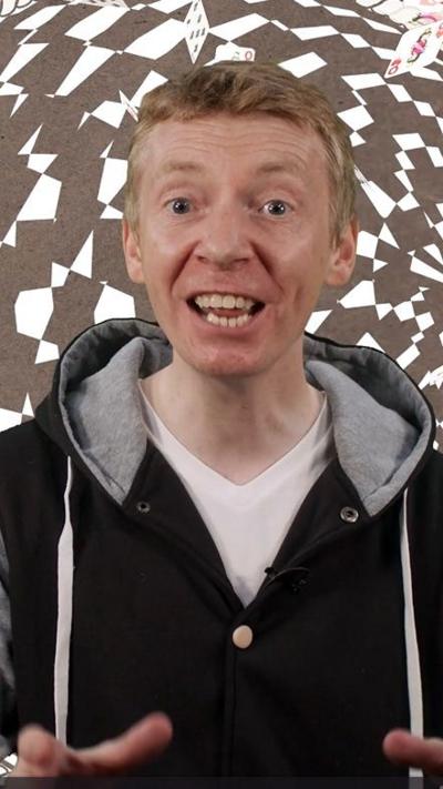 Presenter James Grime wearing a hooded sweatshirt on a black and white background