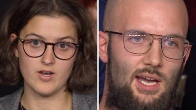 One young woman on the left talking wearing glasses and a young man talking wearing glasses with a beard