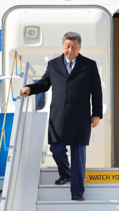 Xi Jinping holding a railing as he descends a plane