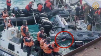 Red circle around man in life jacket holding knife, in a group of people on a boat