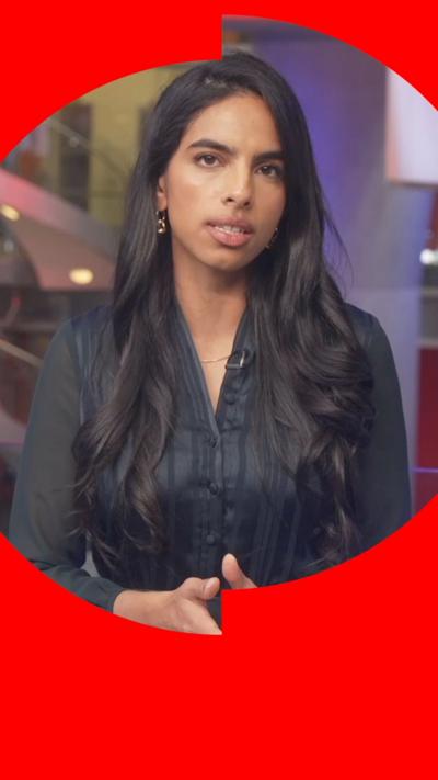 A woman with long black hair, wearing a black shirt, looks to camera, from the BBC newsroom.
