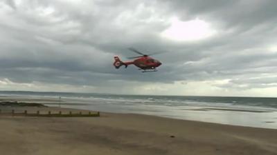 Air ambulance preparing to land on a beach at Tywyn, Gwynedd